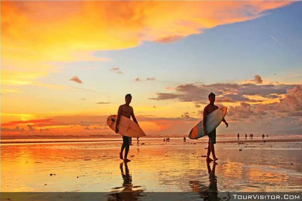 A surfer walking in Kuta beach on the sunset moment